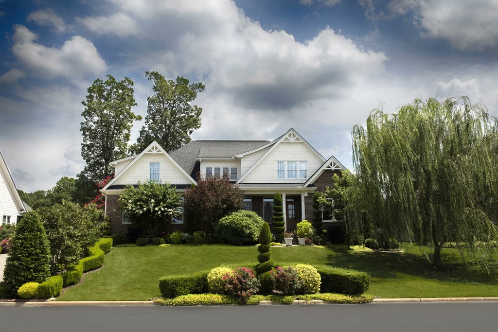 Front yard with trimmed shrubs, flower beds and a green lawn